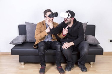 iki hayrete ve Vr gözlük kullanma ve odasında kanepede oturan adam şok 