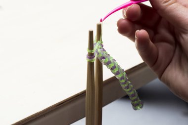 Kadın el örgü iğne ve lastik bantlar ile bilezik yapımı yakın çekim