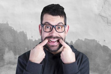 siyah gözlüklü ve kameraya gülümseyen ve parmak ağızda tutan komik aptal adam portresi 