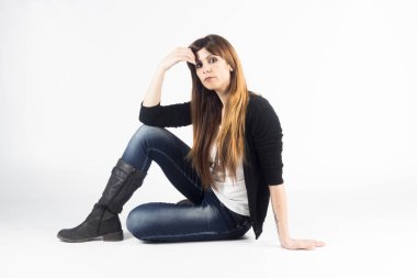 Beyaz arka plan üzerinde Studio katta oturan ve kameraya bakarak güzel İspanyol modeli kadın 