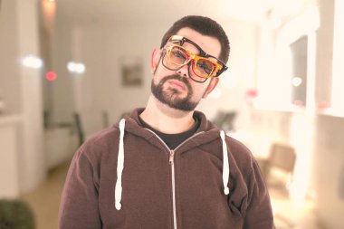 Yüzünde birden çok gözlük takan ve kameraya bakarak üzgün adam 