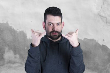 Gri duvar eski adlı dururken elinizle işaret başarı, kutluyor mutlu genç adam 