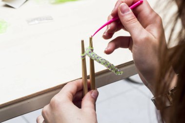 Kadın el giysiler pimleri ve lastik bantlar, kanca kullanma ile bilezik yapımı kısmi görünümü 