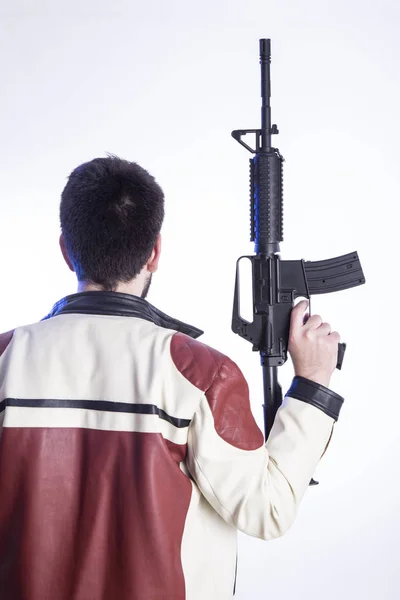スタジオで散弾銃を保持している男の背面図 — ストック写真