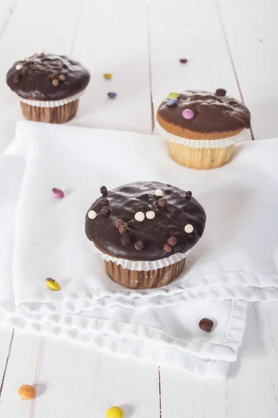 brown chocolate muffins on wooden table with napkin and candies
