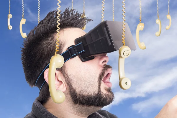 man with opened mouth wearing virtual reality goggles against sky with hanging phones