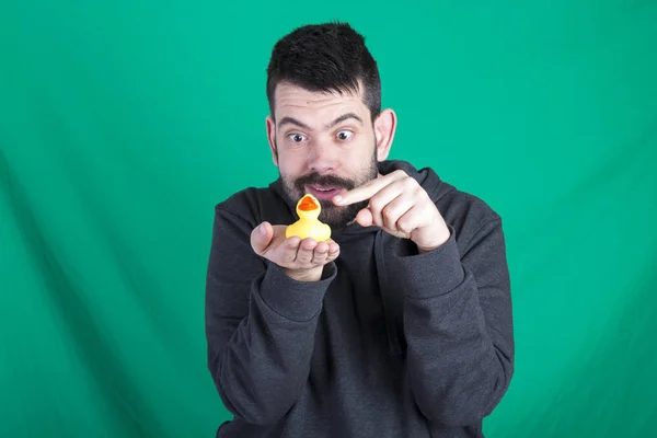 brunette man with stubble pointing finger on yellow rubber duck toy