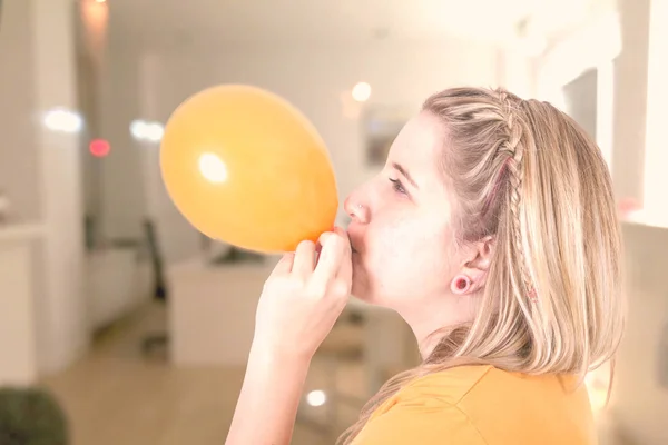 Blonde Frau Bläst Orangefarbenen Luftballon — Stockfoto