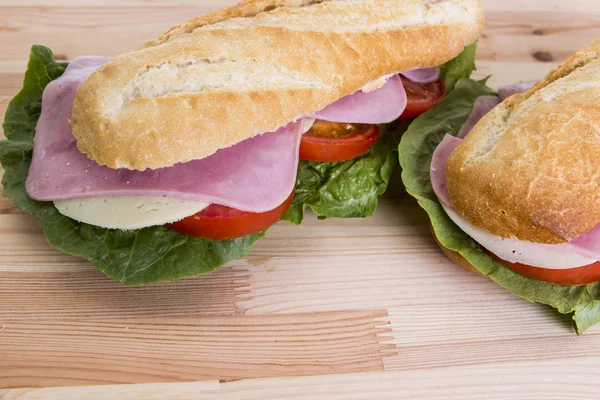 베이컨 고기와 샐러드 나뭇잎 테이블 표면에 바게트 샌드위치를 닫습니다 — 스톡 사진