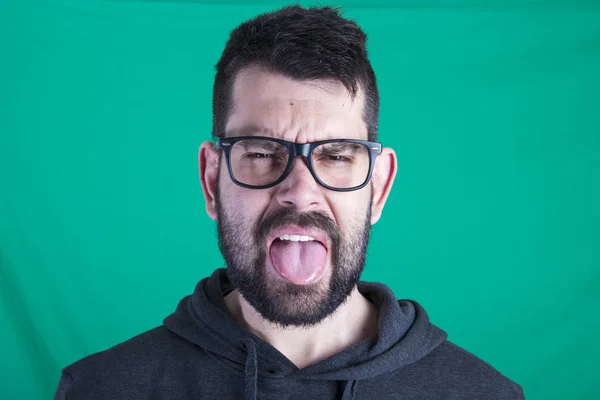 unhappy face of man against green background and showing tongue