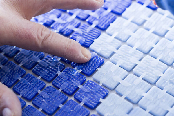 обрезанное изображение человека, работающего с голубой мозаикой
