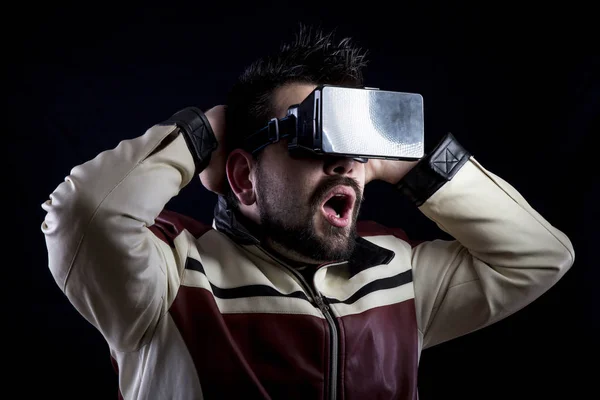 shocked man with opened mouth wearing VR glasses in darkness