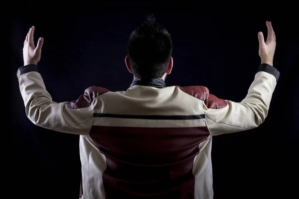 back view of man in studio with black background, wearing white red leather jacket