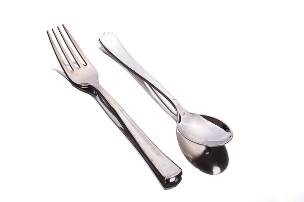 金属叉子和勺子在白色表面与反射 图库照片