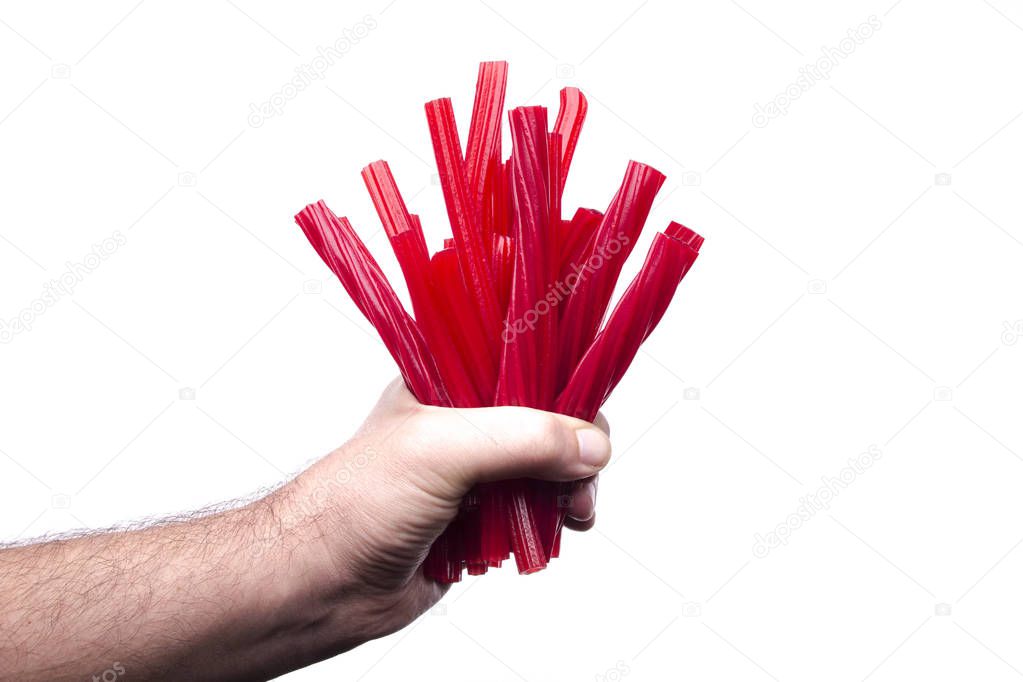 partial view of male hand holding red liquorice candies sticks
