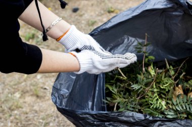bahçede, çalışan adam temizlik kısmi görünümünü siyah çöp kutusuna bırakır 