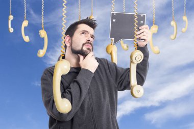 düşünen adam eski moda telefonları cep telefonları asılı ve boş holding Yönetim Kurulu tarafından çevrili gökyüzü karşı