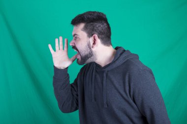 yeşil bir arka plana dayanır kapüşonlu kızgın çığlık atan adam 