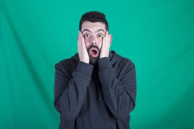 Studio yeşil arka plana karşı duran ve yüz yanaklarda elele ile şok adam 