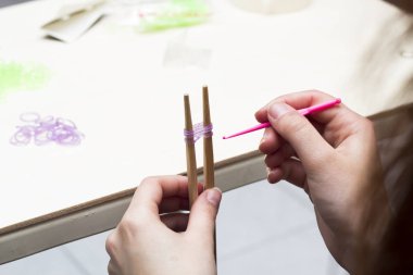 Lastik bant bilezik giyim pimleri ve pembe kanca ile masada yapımı kadının kırpılmış görüntü 