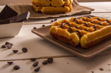 plaka, çikolata şurubu ile pişmiş Belçika Waffle kase masada çikolatalı dilimler 