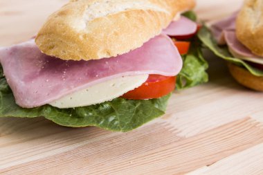 Baget sandviçler pastırma et ve yeşil salata yaprakları, gıda ahşap masa yüzeyi ile yakın çekim