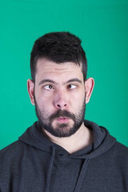 yeşil arka planı stüdyosunda poz şaşı gözlü esmer adam 
