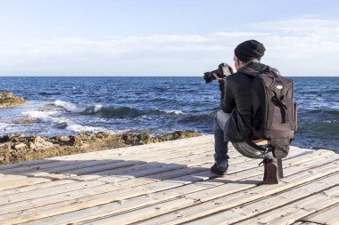 Fotoğrafçı adam fotoğraf makinesi fotoğraf denizde su çekme ile şapkalı 