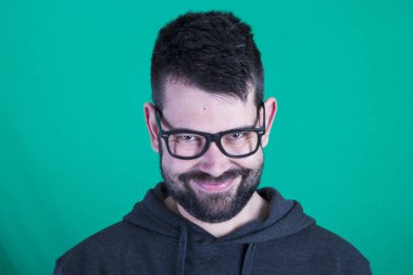 poz ve kameraya bakarak yeşil bir arka plana dayanır mutlu utangaç adam portresi