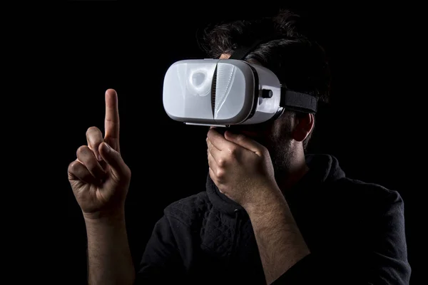 afraid man wearing VR glasses in darkness and pointing finger up