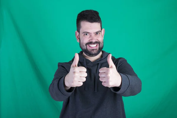 Portret Van Gelukkig Man Tegen Een Groene Achtergrond Gebaren Duimschroef — Stockfoto