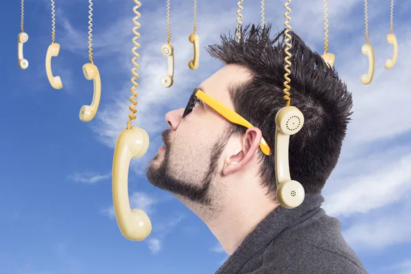 昔ながらの古い電話機を掛けることによって囲まれた曇り空に対して眼鏡を着用の男 — ストック写真