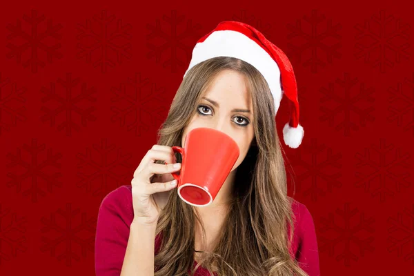 Brünette Frau Mit Weihnachtsmannhut Trinkt Kaffee Studio Vor Rotem Hintergrund — Stockfoto