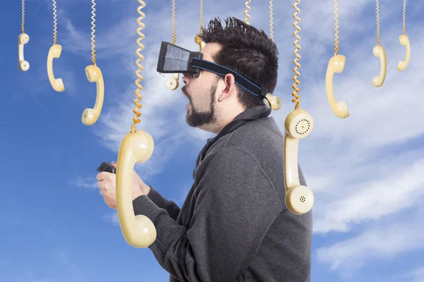 家伙使用 眼镜小工具和游戏操纵杆控制器 天空与挂老式电话手机 — 图库照片