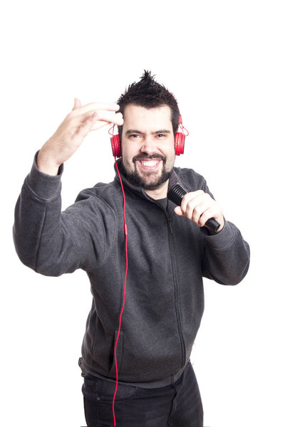 smiling Caucasian singer man holding and singing in microphone in studio and looking at camera