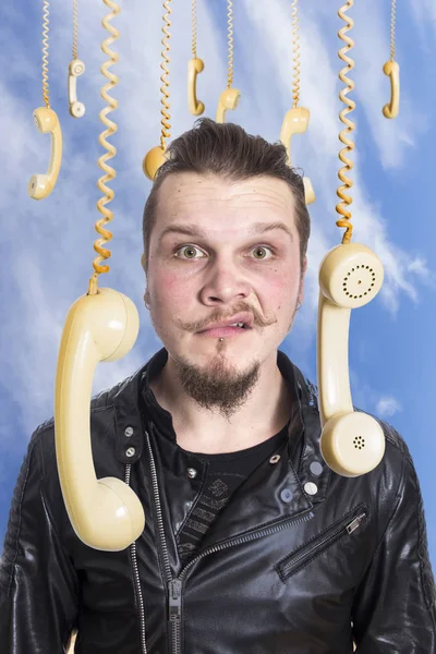 funny unhappy face of man against sky surrounded by hanging old fashioned phones handsets