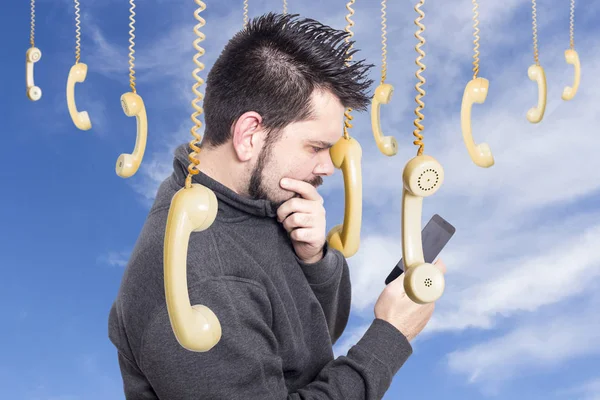 man against sky surrounded by hanging Old Fashioned Phone Handset browsing modern mobile phone