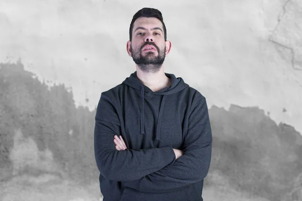 caucasian man with stubble posing on camera with arms crossed