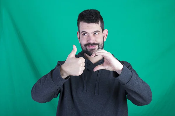 Hombre Con Capucha Posando Sobre Fondo Verde Haciendo Gestos Con —  Fotos de Stock