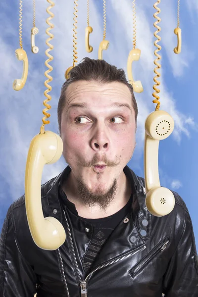 funny face of man against sky surrounded by hanging old fashioned phones handsets