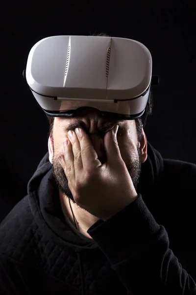 tired man wearing with VR glasses in darkness, touching tired eyes