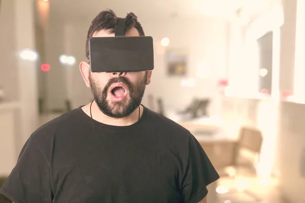 shocked man with opened mouth wearing VR glasses at home in room