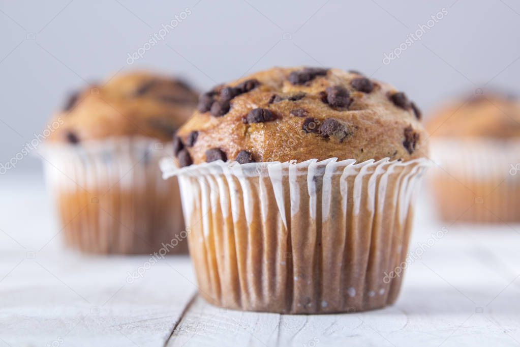 close up of cupcakes decorated with chocolate chips on wooden table surface 