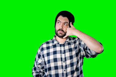 Yakışıklı sakallı adam yeşil stüdyo geçmişine telefon jesti yapıyor.