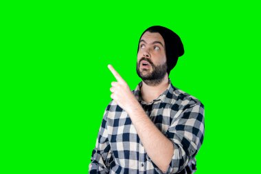 Genç adam fotokopi alanını gösteriyor ve bakıyor. Yakışıklı genç iş adamı yeşil arka planda izole edilmiş..