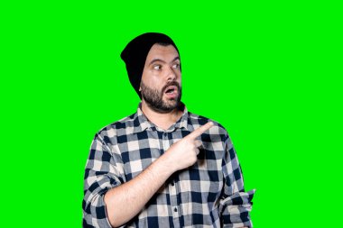 Genç adam fotokopi alanını gösteriyor ve bakıyor. Yakışıklı genç iş adamı yeşil arka planda izole edilmiş..