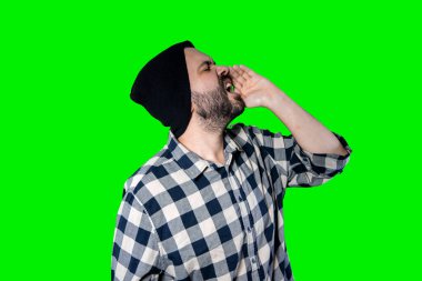 Çığlıklar, nefret, öfke. Kroma stüdyosunun arka planında ağlayan duygusal sinirli bir adam. Duygusal ve genç bir yüz. Yarım boy erkek portresi. İnsani duygular, yüz ifadesi kavramı.