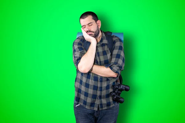 Bored young bearded traveler guy over green studio background
