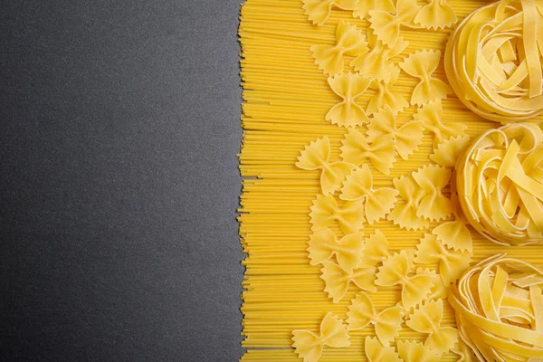 Vista superior de pasta o espaguetis italianos sobre fondo de pizarra de piedra negra. Copiar espacio — Foto de Stock