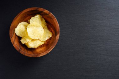 Siyah arka planda, üstten görünüm, kase gevrek patates cipsi alanı Kopyala